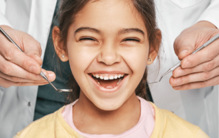 Image of child smiling while dentist holds dental tools